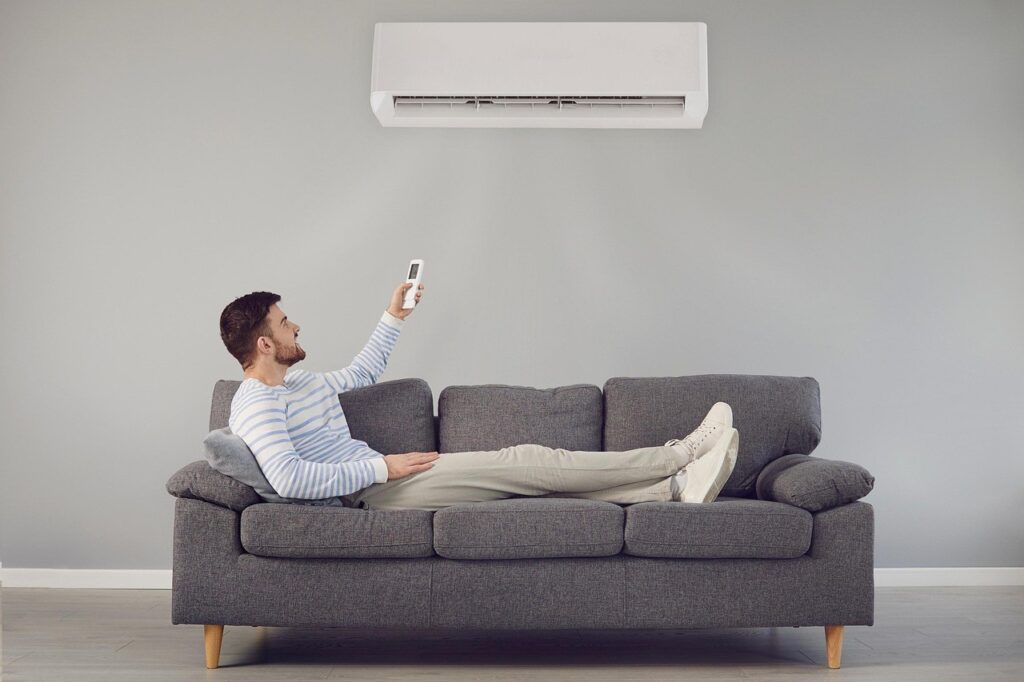 Homme réglant la télécommande d'un climatiseur mural dans un salon