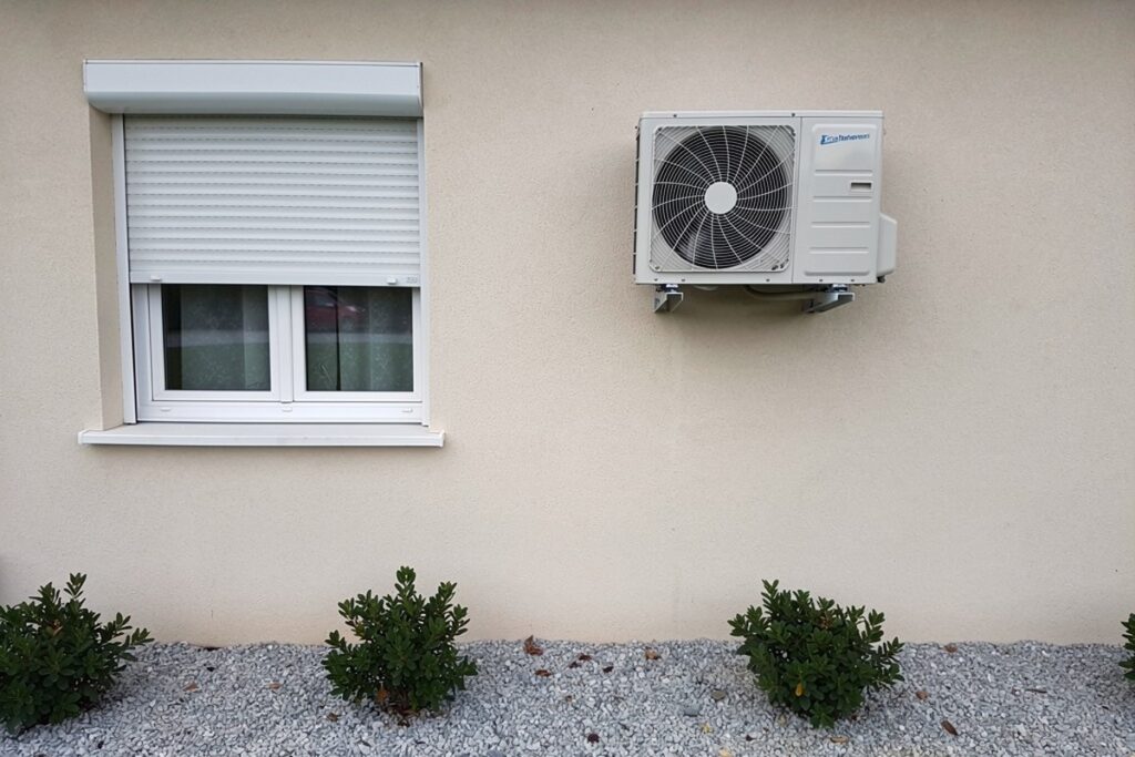 Unité extérieure de climatiseur fixée sur la façade sous une fenêtre à volet roulant