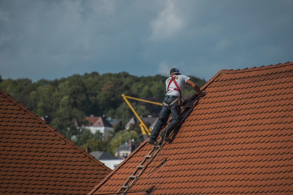 Sarking : l'isolation de toiture qui protège été comme hiver 6 Couvreur sur un toit de maison en tuiles rouges