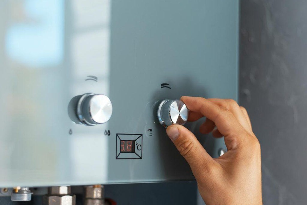 Main réglant la molette de température d'une chaudière gaz murale