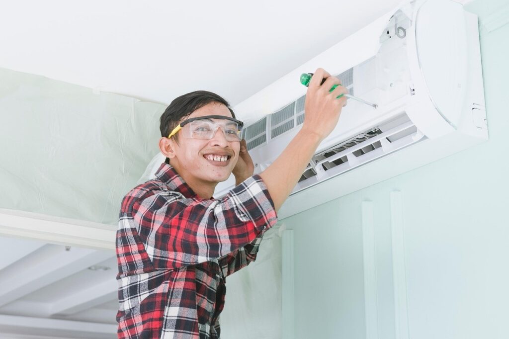 Mise en service d'une PAC : le piège quand on l'achète en ligne 4 Technicien souriant fixant une unité intérieure de climatisation murale