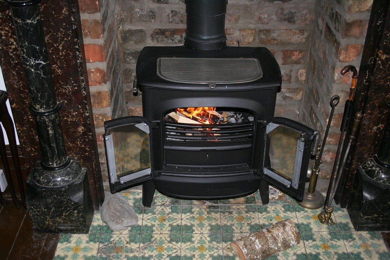 Prime Air Bois : l'aide méconnue pour remplacer un vieux poêle qui pollue 2 Poêle à bois installé dans une cheminée ancienne en briques, portes ouvertes sur le feu
