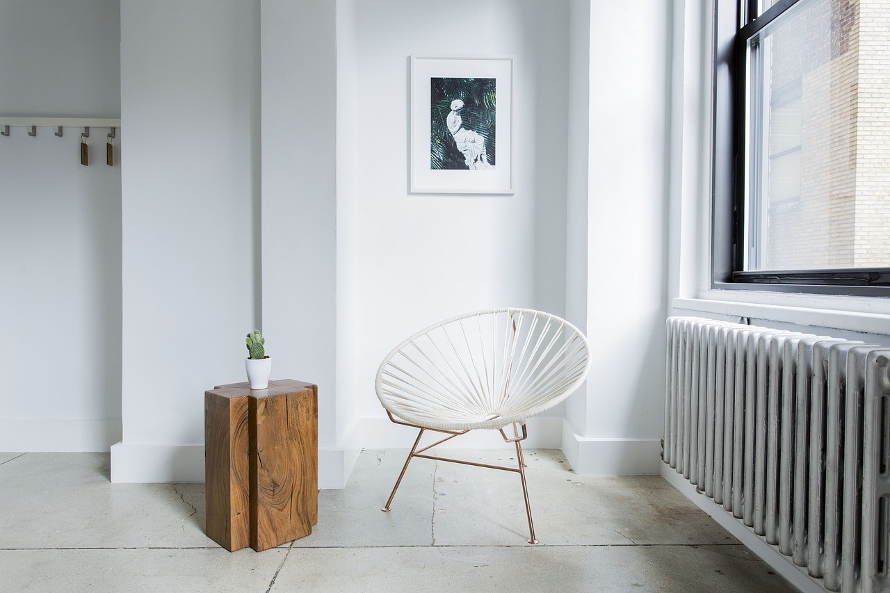 Pièce claire et épurée avec un radiateur à eau sous une fenêtre, ambiance chaleureuse